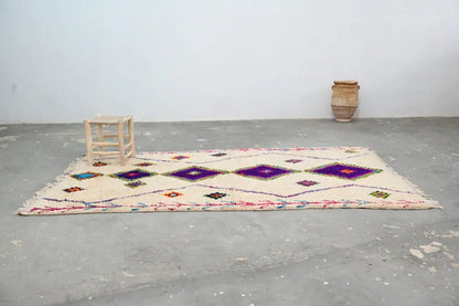 Cream-colored moroccan handmade traditional azilal rug with bold purple diamond patterns and colorful geometric accents