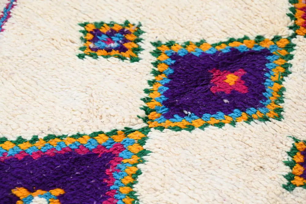Vibrant moroccan handmade traditional azilal rug with plush cream background and bold purple orange green and blue motifs