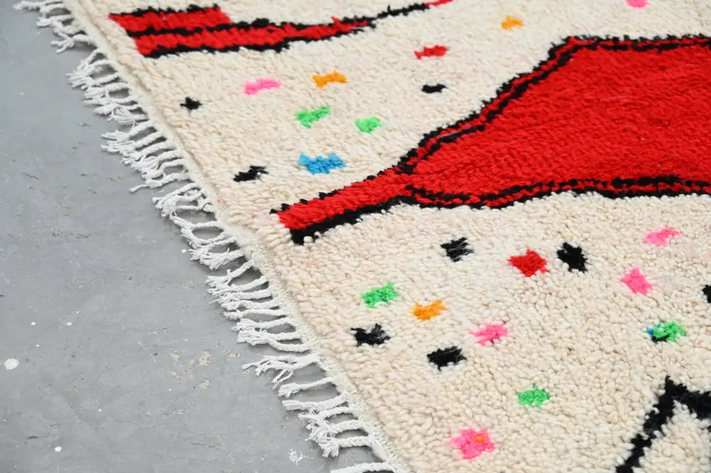 Cream-colored moroccan handmade traditional azilal rug with bold red black geometric patterns and colorful polka dots