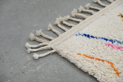 Cream-colored moroccan handmade traditional azilal rug with fluffy texture and colorful blue pink orange geometric patterns
