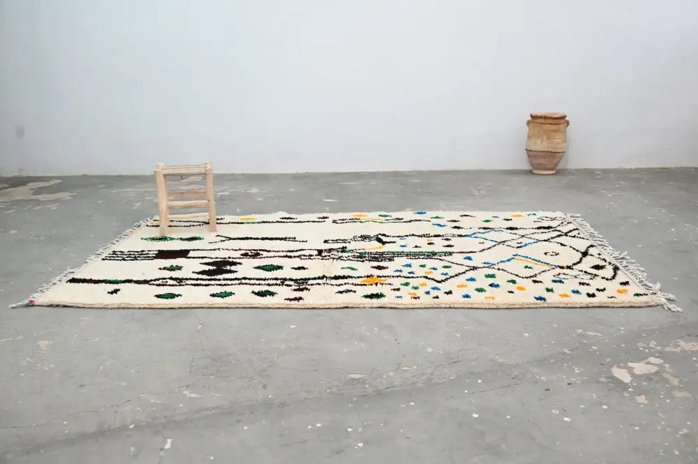 Cream-colored moroccan handmade traditional azilal rug with black green blue geometric patterns and fringed edges 273 x 155 cm