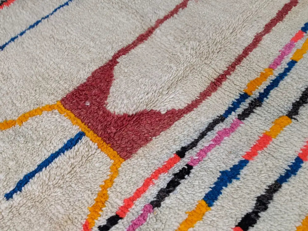 A moroccan handmade azilal rug by decorbites featuring bold red blue orange pink and black geometric patterns on pure natural wool