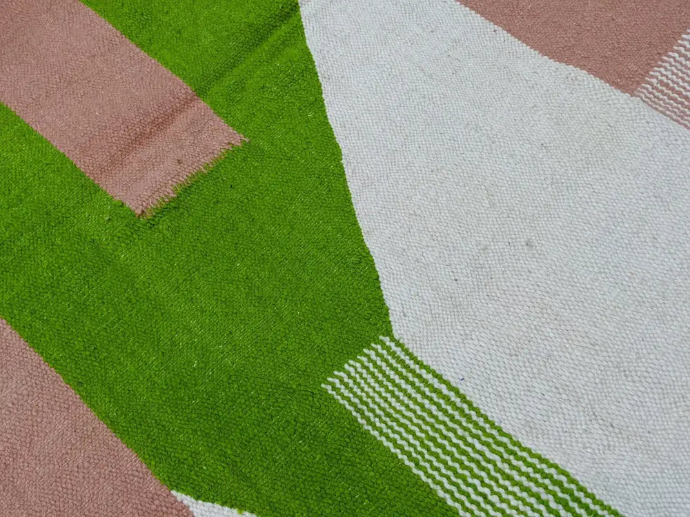 A moroccan handmade traditional azilal rug with textured geometric patterns in bold green white and dusty rose by DecorBites