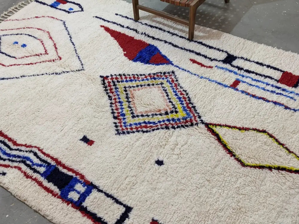 Cream-colored plush wool moroccan handmade traditional azilal rug with bold red blue yellow and black geometric patterns