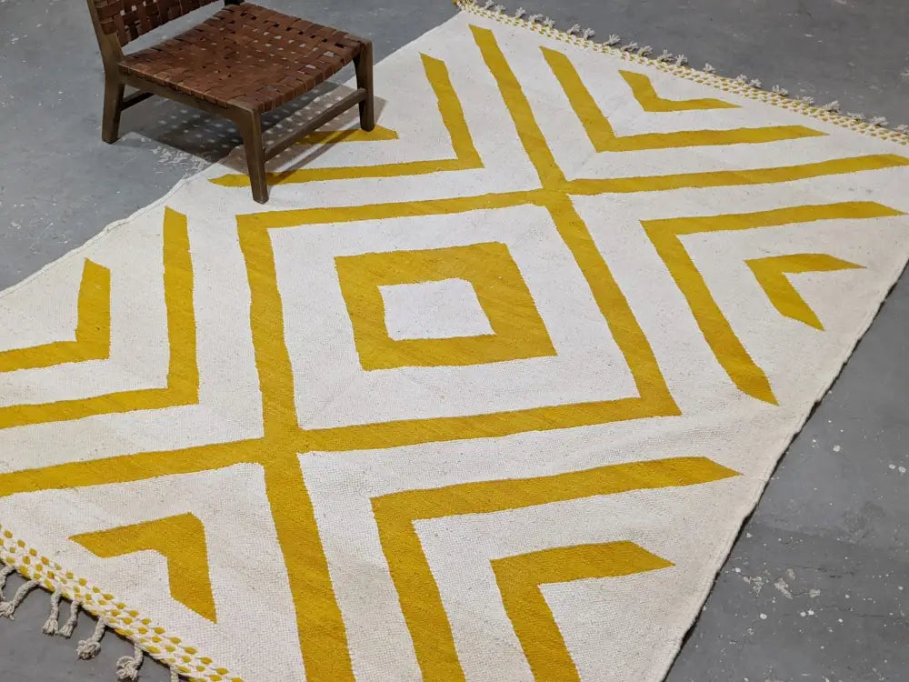 Cream-colored moroccan handmade traditional azilal rug with bold mustard-yellow geometric patterns and fringed edges