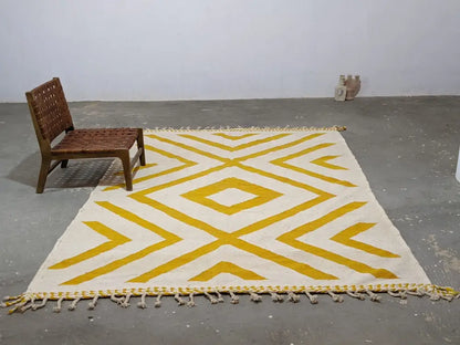 A cream-colored moroccan handmade traditional azilal rug with bold mustard-yellow geometric patterns and fringed edges