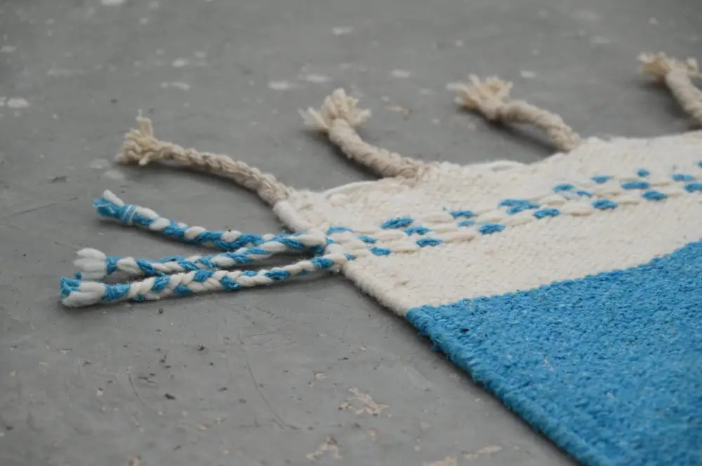 A moroccan handmade traditional azilal rug with cream and blue colors and braided tassels by DecorBites™