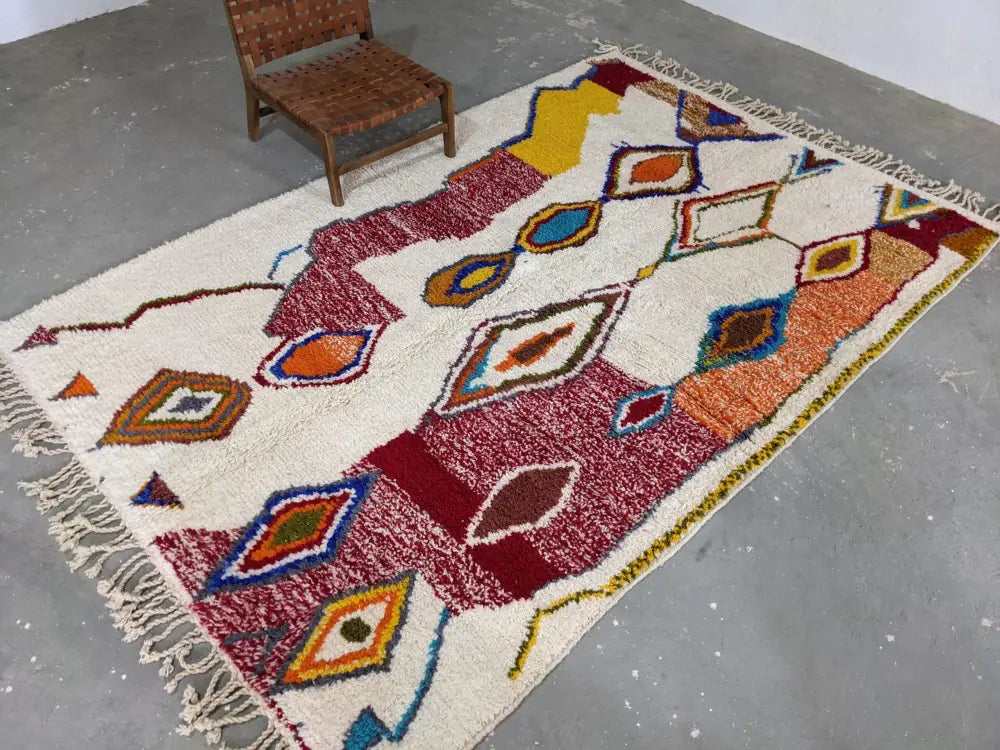 A vibrant moroccan handmade traditional azilal rug with cream base and bold geometric patterns in reds and blues