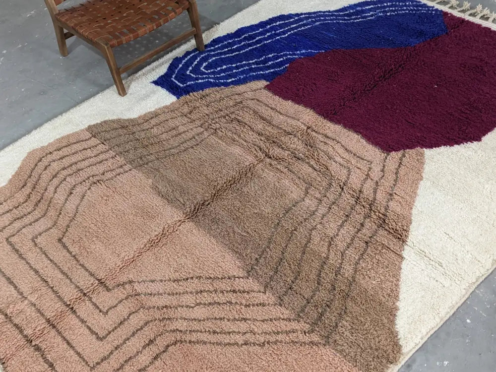 A moroccan handmade traditional azilal rug with a cream base and dusty rose, burgundy, navy blue, and beige wool fibers