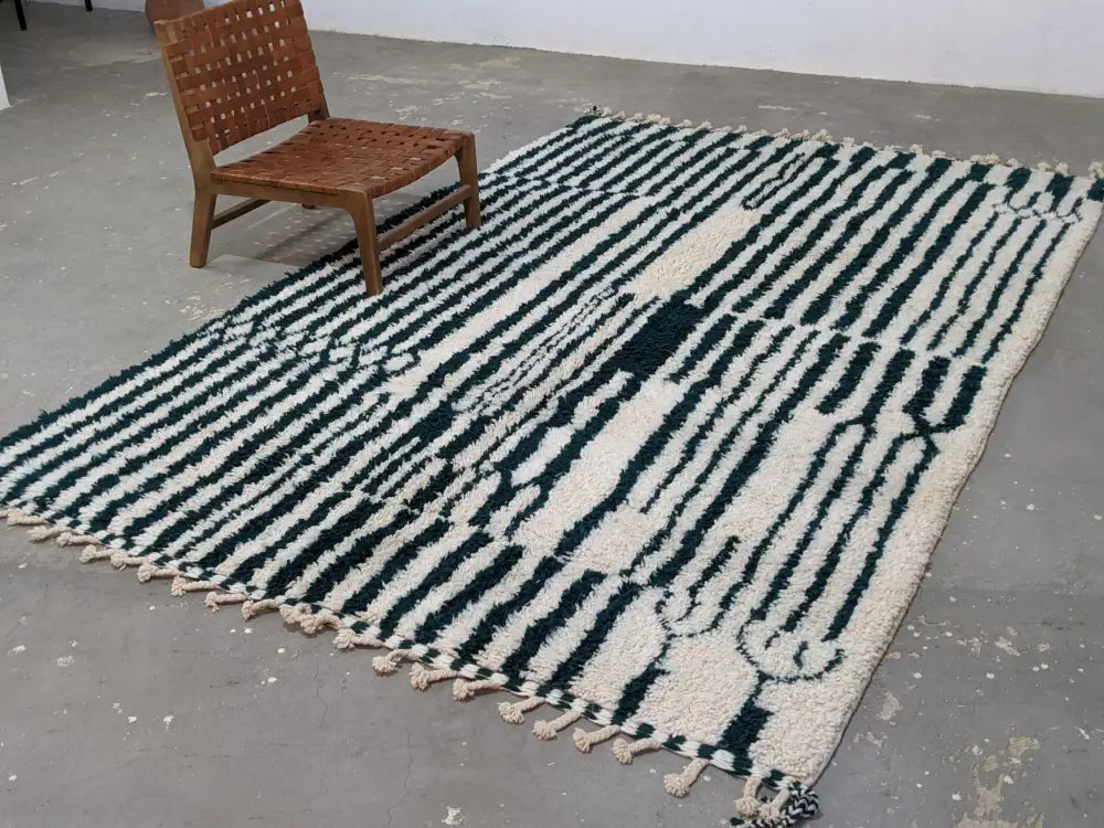 A chunky moroccan handmade traditional azilal rug with bold black and cream wool stripes and tassels by DecorBites