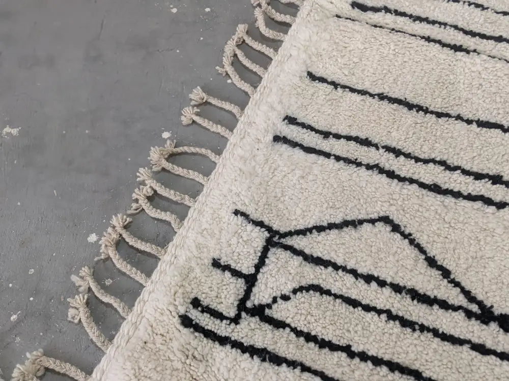 Cream-colored decorbites™ moroccan handmade traditional azilal rug with black geometric patterns and fringed edges 317 x 215 cm