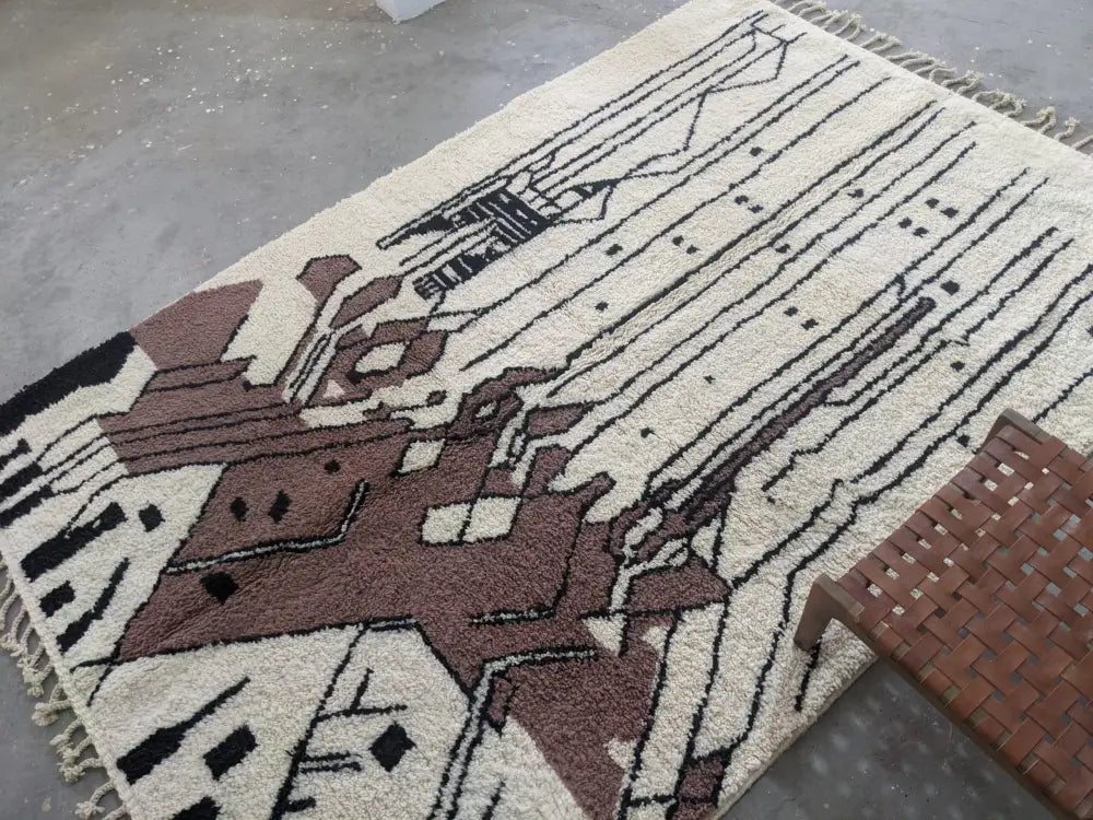 Cream-colored moroccan handmade traditional azilal rug with abstract black and brown geometric patterns and fringed edges