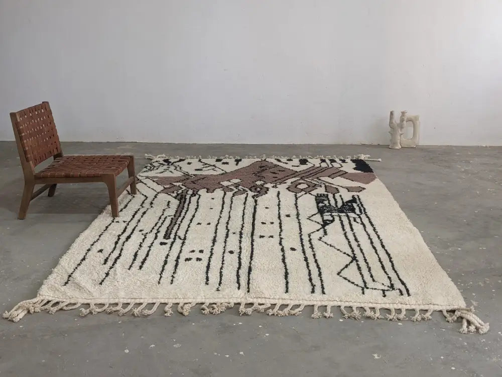 Cream-colored moroccan handmade traditional azilal rug with black and brown geometric patterns and fringed edges