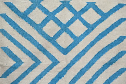 A cream-colored DecorBites™ moroccan handmade traditional azilal rug featuring bold blue geometric diamonds and stripes