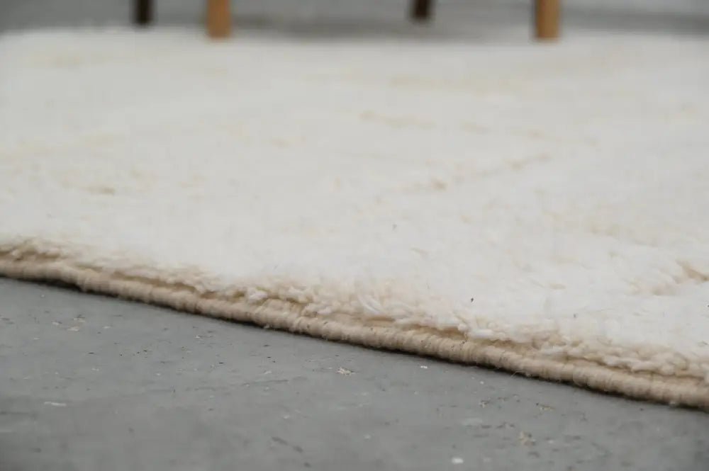 Cream-colored plush shaggy beni ouarain carpet with soft textured surface and neatly finished edge moroccan handmade