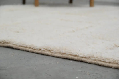 Cream-colored plush shaggy beni ouarain carpet with soft textured surface and neatly finished edge moroccan handmade