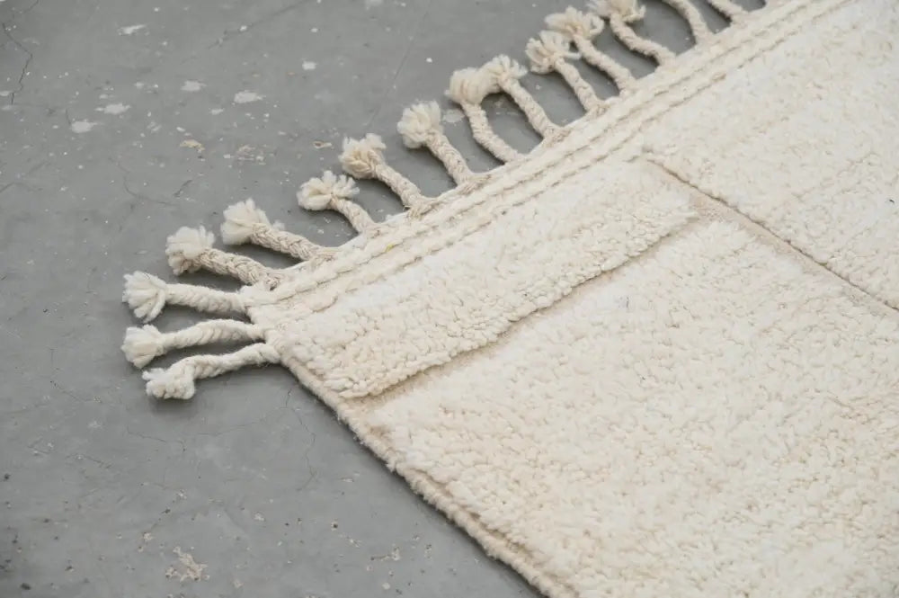 Cream-colored moroccan handmade beni ouarain carpet with plush texture and twisted tassel fringe decorbites 305 x 202 cm