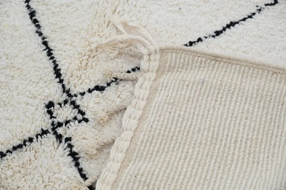 Cream-colored beni ouarain carpet with black geometric patterns and braided fringe moroccan handmade traditional rug