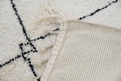 Cream-colored beni ouarain carpet with black geometric patterns and braided fringe moroccan handmade traditional rug