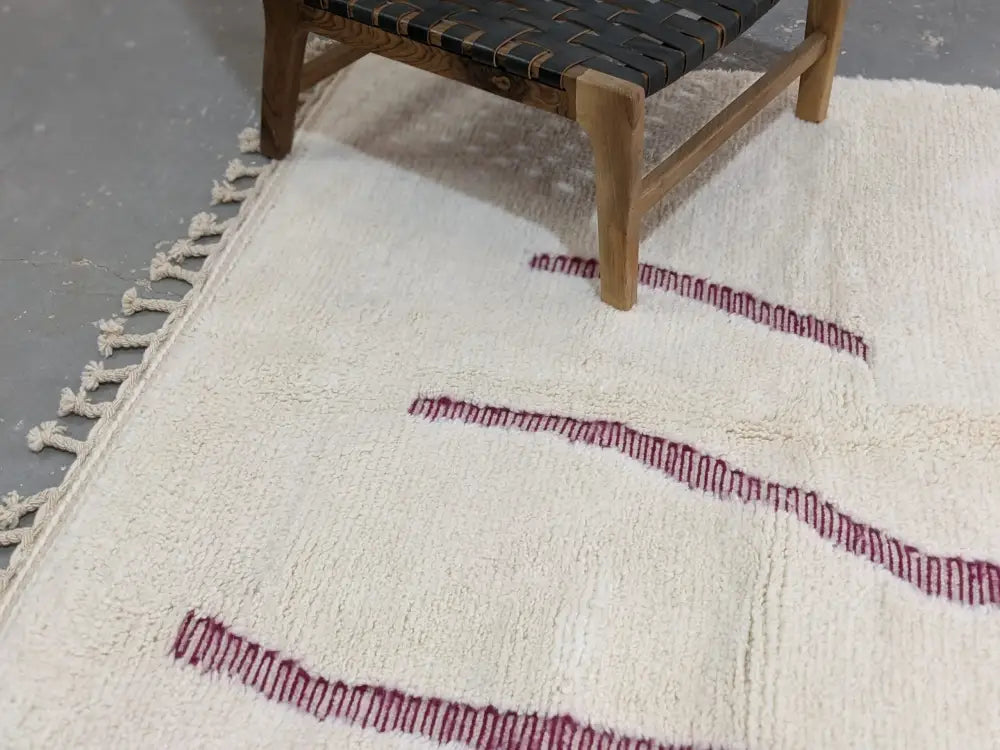 Cream-colored beni ouarain rug with textured wool surface and bold red stitched geometric edges moroccan handmade decorbites
