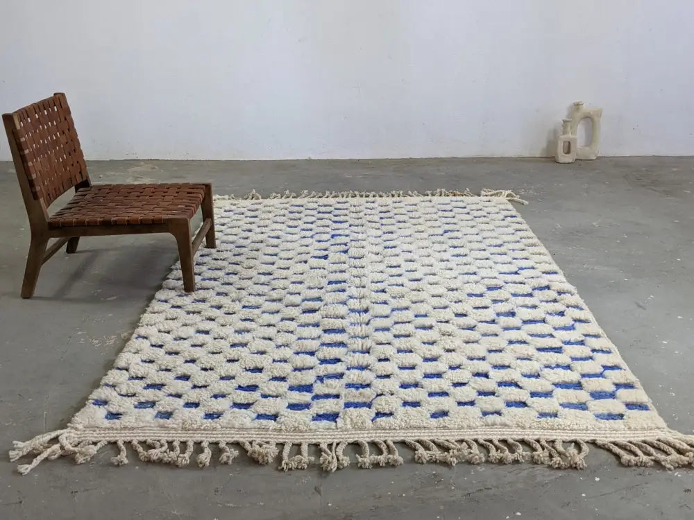 Cream-colored moroccan handmade beni ouarain rug with blue and white geometric woven squares and fringed edges