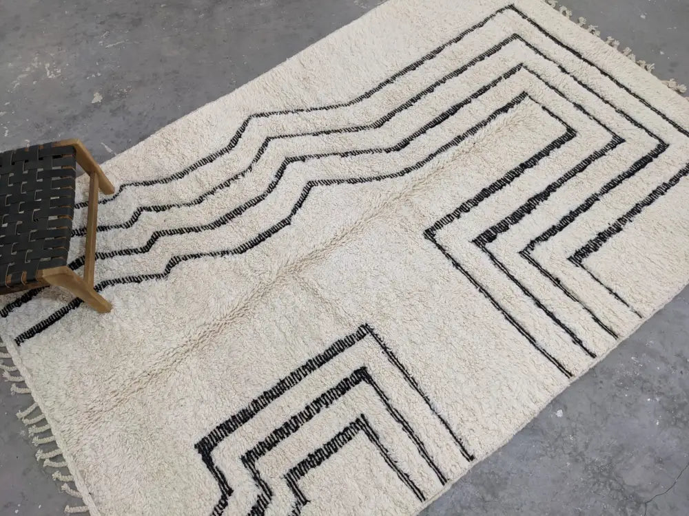 Cream-colored plush wool beni ouarain rug with bold black geometric zigzag patterns and fringed edges moroccan handmade