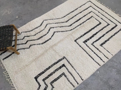 Cream-colored plush wool beni ouarain rug with bold black geometric zigzag patterns and fringed edges moroccan handmade