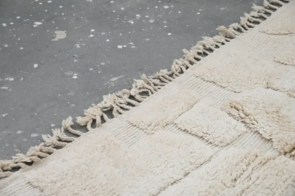 Cream-colored textured wool beni ouarain rug with geometric patchwork and fringed edge moroccan handmade decorbites