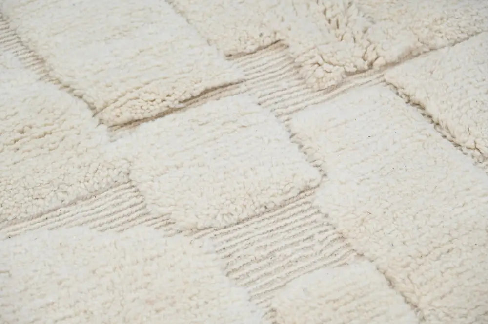 Cream-colored moroccan handmade beni ouarain rug with plush textured patchwork design and ribbed borders 285 x 210 cm