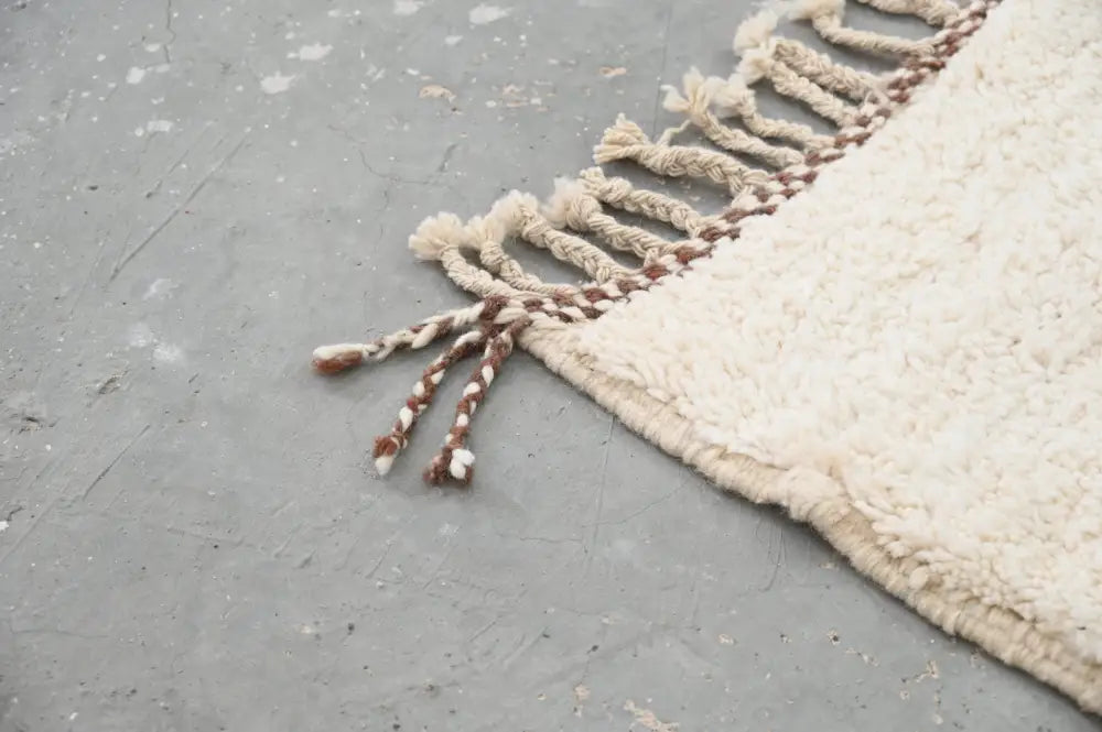 Cream-colored plush wool beni ouarain rug with fringed edge and braided cream and brown tassels 290 x 214 cm