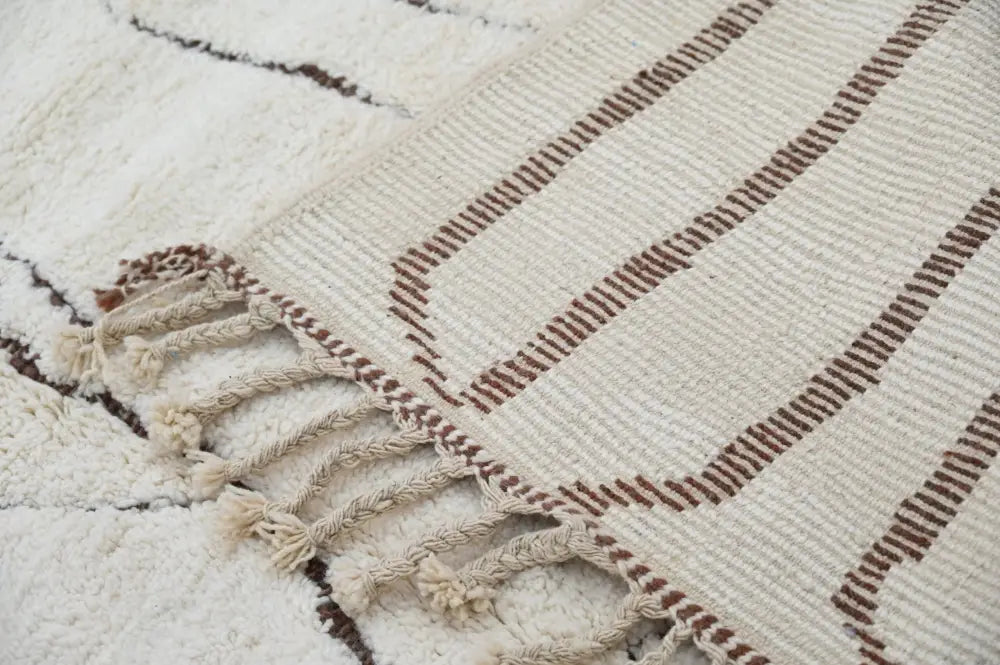 Cream-colored beni ouarain rug with brown geometric stripes and textured fringe by decorbites 290 x 214 cm