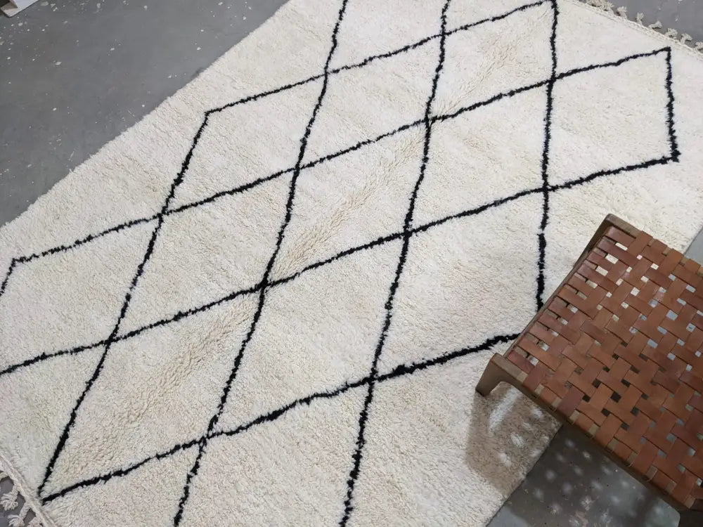 Cream-colored moroccan handmade beni ouarain rug with bold black geometric diamond pattern and fringed edges 292 x 202 cm