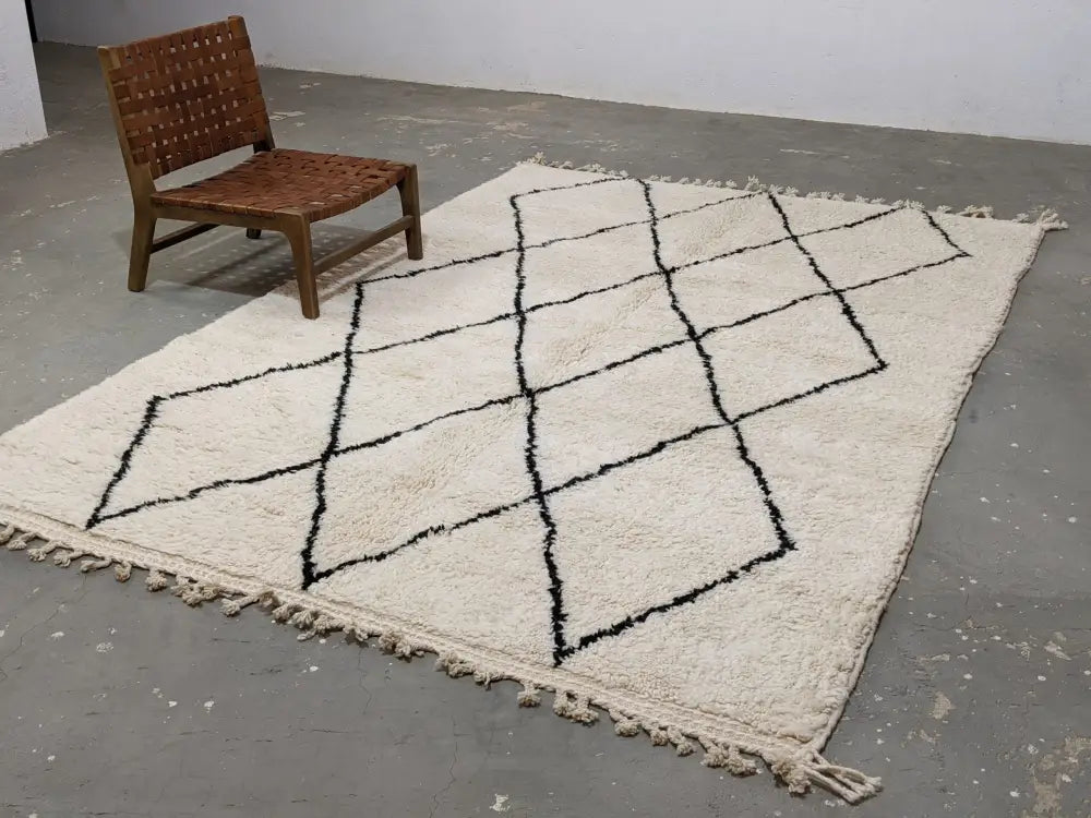 Cream-colored moroccan handmade beni ouarain rug with black geometric diamond pattern and fringed edges 292 x 202 cm