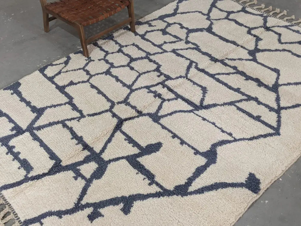 Cream-colored beni ouarain rug with bold navy blue geometric pattern and fringed edges moroccan handmade decorbites