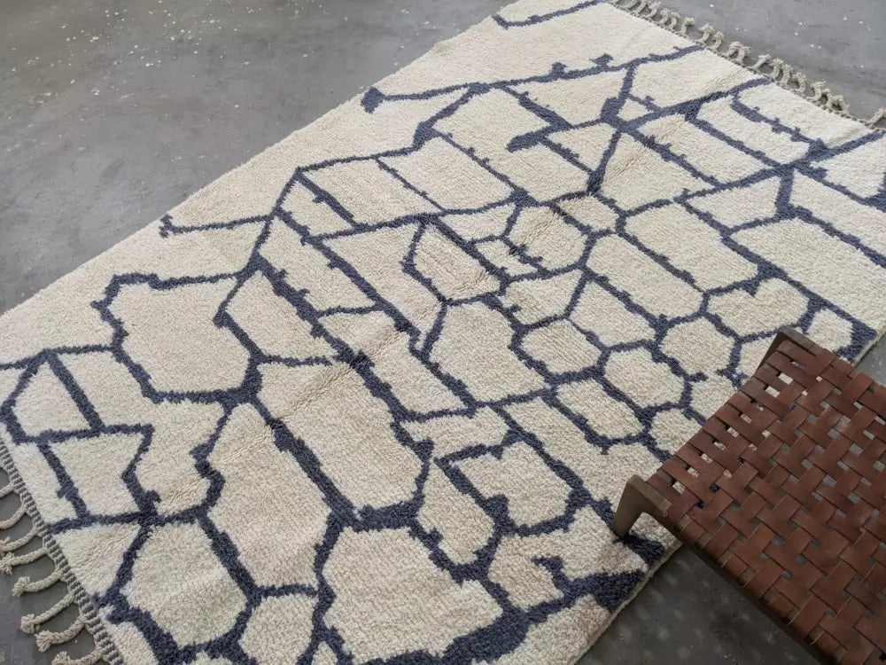 Cream-colored beni ouarain rug with bold navy geometric pattern fringed edges and textured weave moroccan handmade