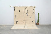 Cream-colored moroccan handmade beni ouarain rug with black geometric patterns and fringed edges 300 x 200 cm