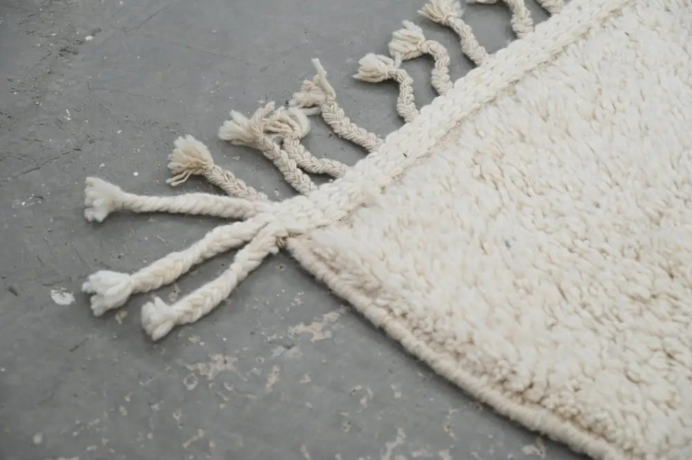 Cream-colored moroccan handmade beni ouarain rug with plush wool texture and braided tassels edge 300 x 200 cm