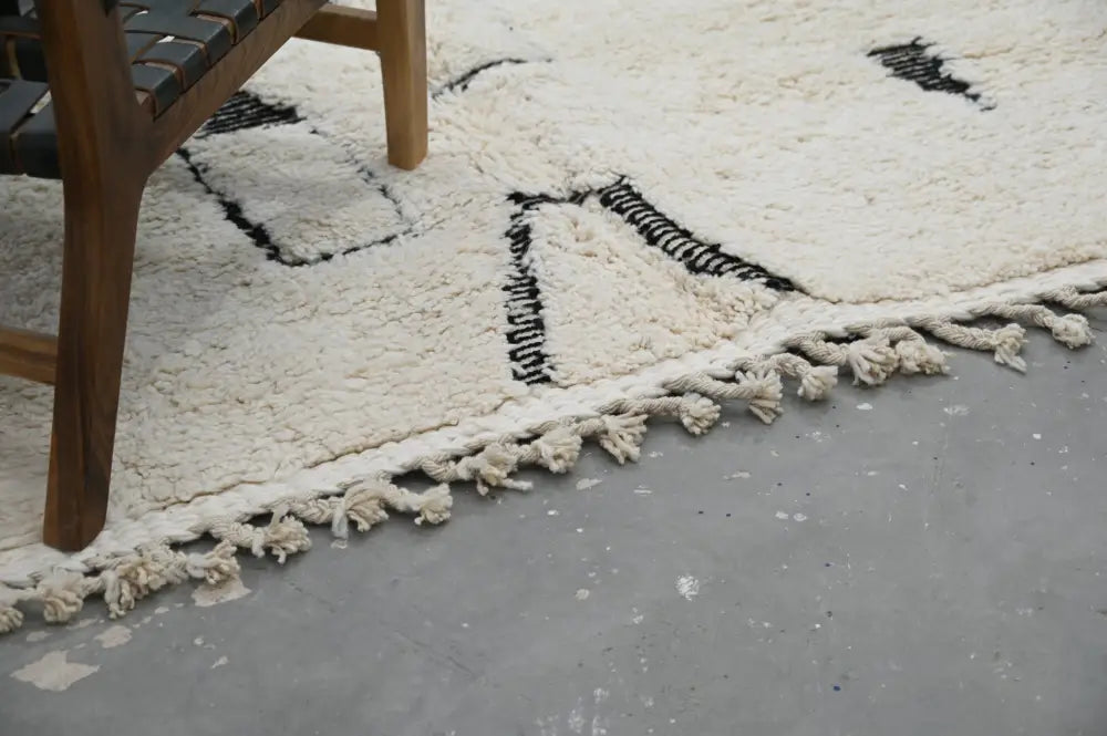 Cream-colored plush wool beni ouarain rug with black geometric patterns and fringed edges moroccan handmade design