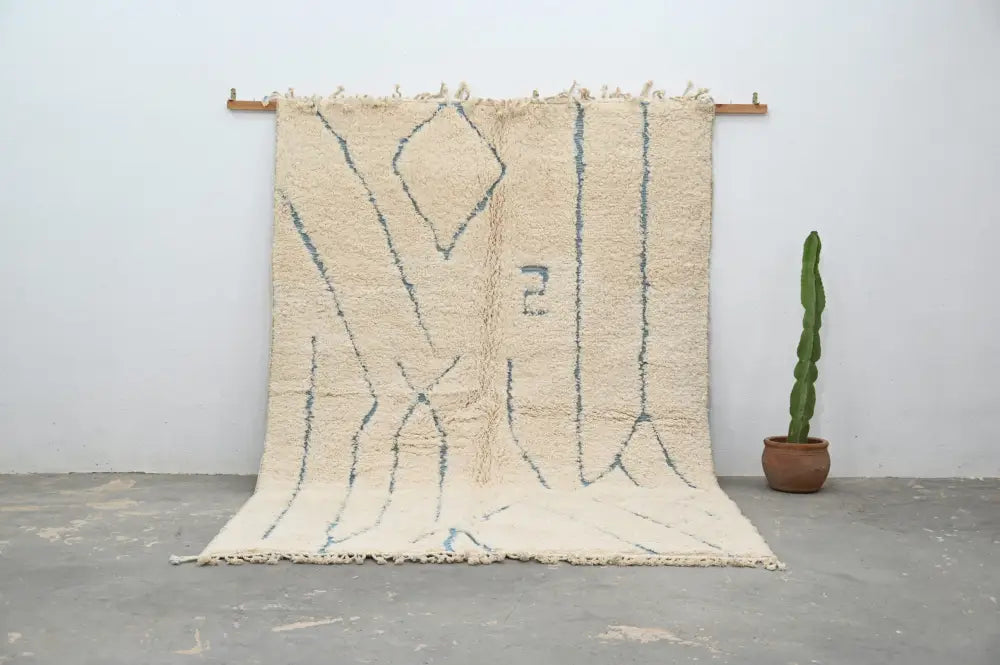 Cream-colored moroccan handmade beni ouarain rug with muted blue geometric patterns and fringed woolen texture 300 x 205 cm