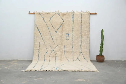Cream-colored moroccan handmade beni ouarain rug with muted blue geometric patterns and fringed woolen texture 300 x 205 cm