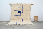 Beige moroccan handmade beni ouarain rug with bold blue geometric patterns and fringed edges 300 x 207 cm