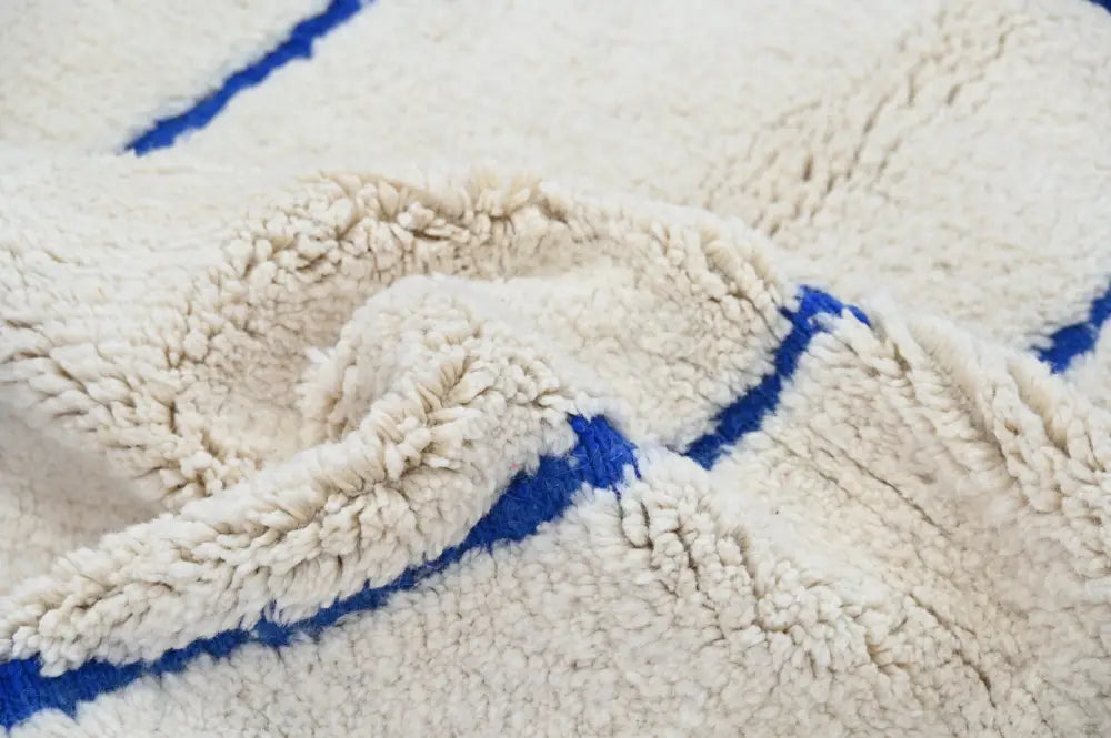 Cream-colored beni ouarain rug with bold blue geometric stripes moroccan handmade traditional shearling blanket