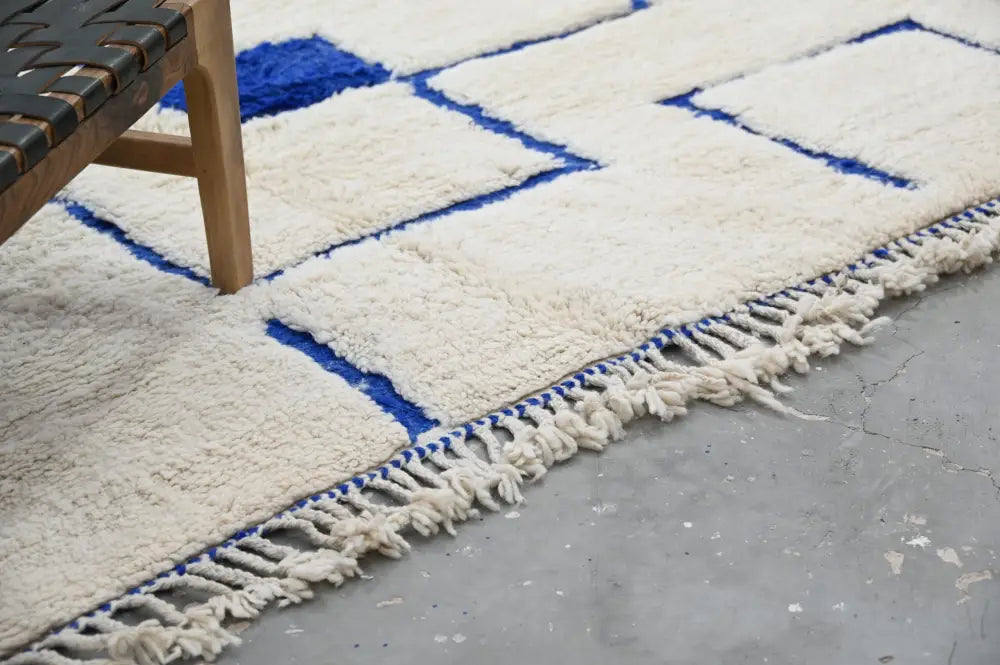 Cream-colored beni ouarain rug with bold blue geometric patterns and fringed edges moroccan handmade wool decorbites