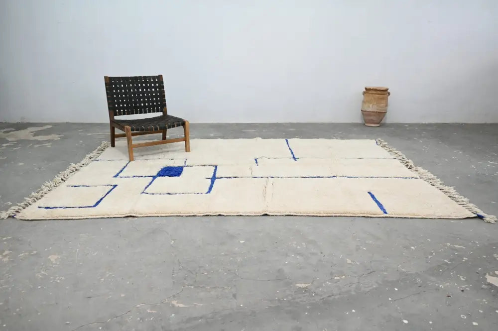 Cream-colored beni ouarain rug with bold blue geometric patterns and fringed edges moroccan handmade traditional design