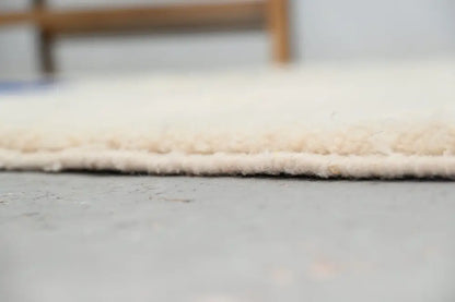 Cream-colored plush shaggy beni ouarain rug with soft textured surface and neatly finished edge moroccan handmade