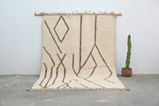 Beige moroccan handmade beni ouarain rug with bold brown geometric patterns and fringed edges by DecorBites™