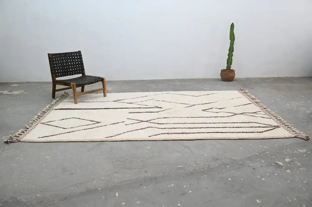 Cream-colored beni ouarain rug with black geometric patterns and fringed edges moroccan handmade traditional wool