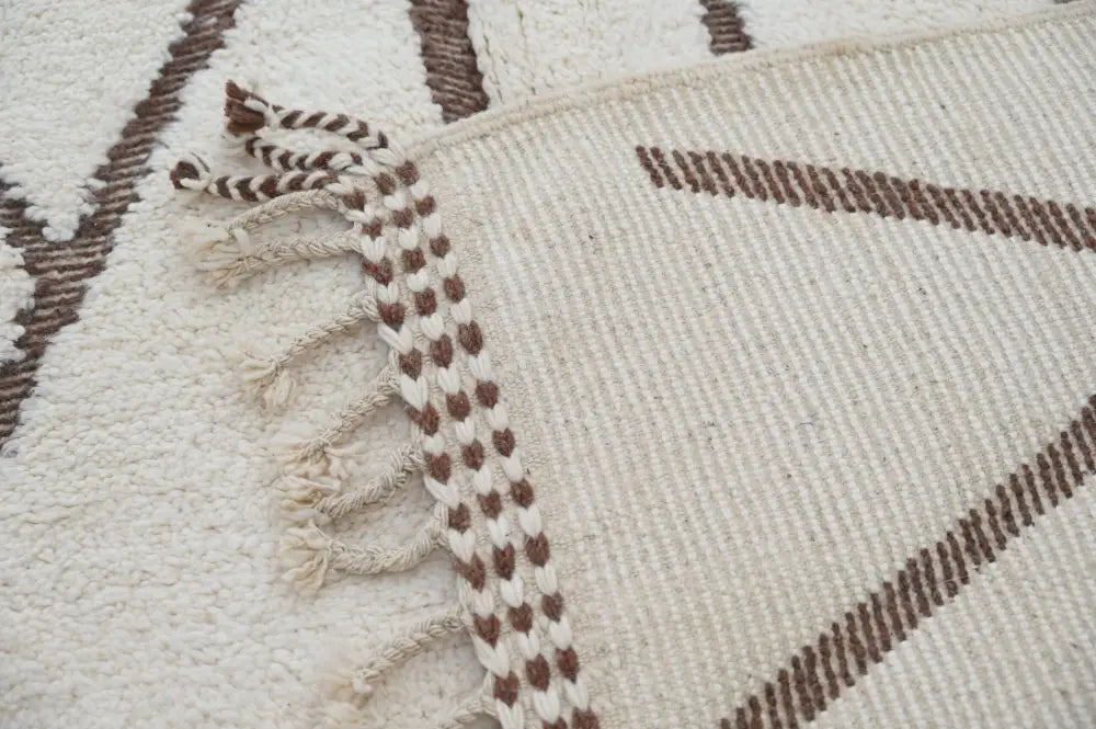 Cream-colored woven beni ouarain rug with brown geometric patterns and braided fringe moroccan handmade traditional design
