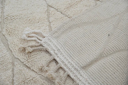 Cream-colored textured moroccan handmade beni ouarain rug with woven geometric patterns and fringed edges 300 x 211 cm