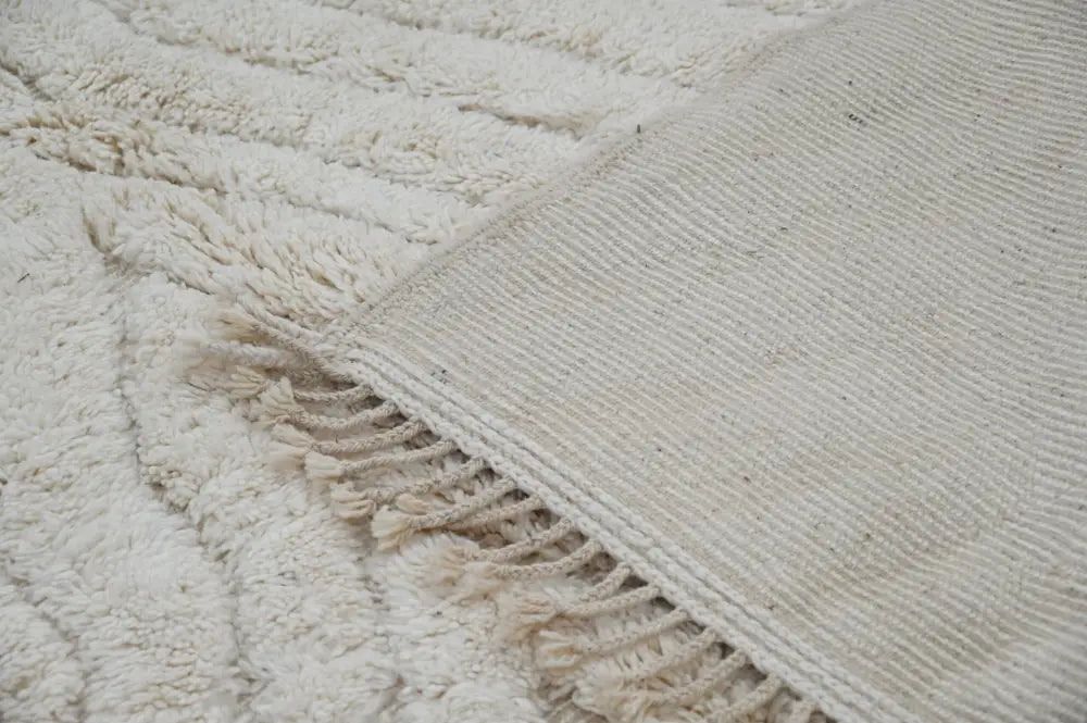 Cream-colored plush wool beni ouarain rug with textured ribbed border and fringed edge moroccan handmade decorbites